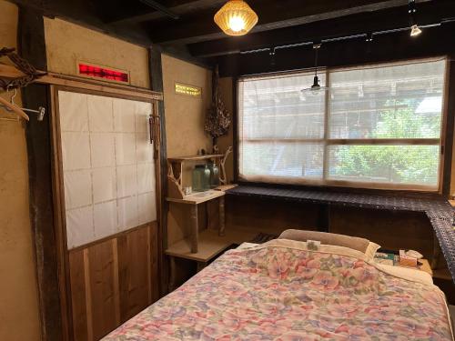 a bedroom with a bed and a window at 木古里ゲストハウス Kicoli guesthouse in Chizu