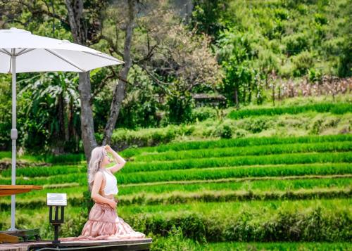 a woman in a pink dress standing under an umbrella at MT House Sa Pa - Mountain & Terraced fields View And Trekking Tour in Sa Pa