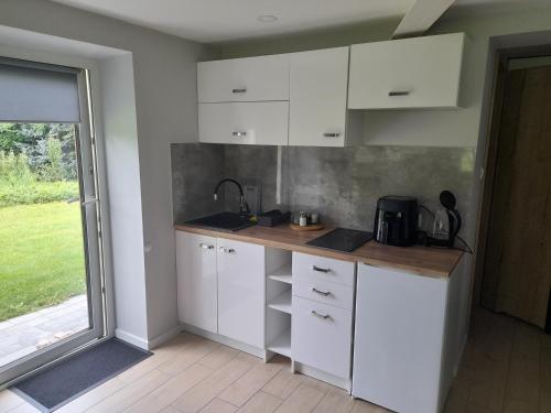 a kitchen with white cabinets and a large window at Apartament z ogrodem in Przemyśl