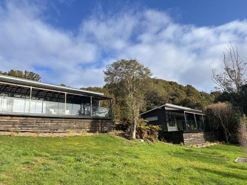 a building with windows on a grassy field at Beaks and Feathers Boutique Accommodation on Stewart Island in Stewart Island