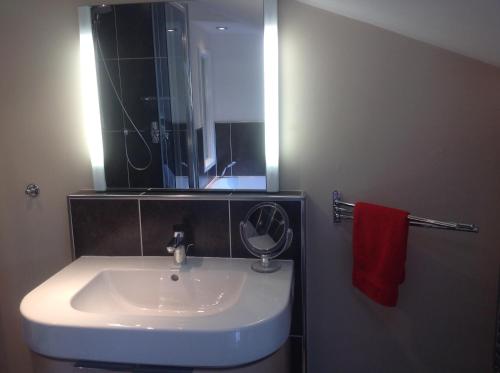 a bathroom sink with a mirror and a red towel at The Greyhound - Historic former Inn in Glemsford