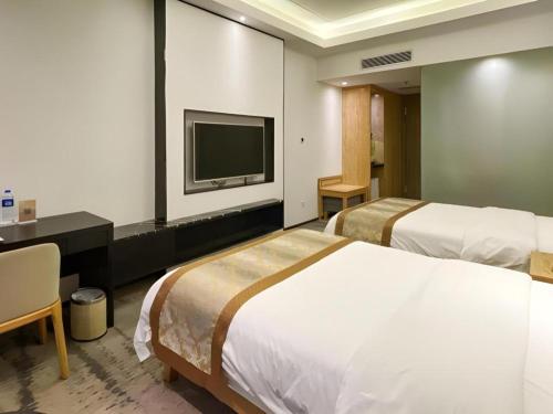 a hotel room with two beds and a flat screen tv at Golden Central Hotel Shenzhen in Shenzhen