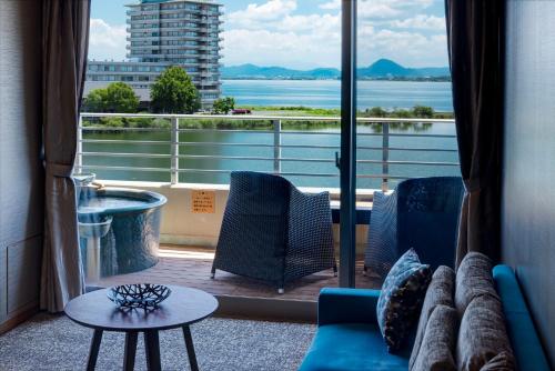 a room with a couch and a view of a balcony at Biwako Ryokusuitei in Otsu
