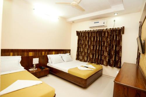 a hotel room with two beds and a window at Sai Vishwakarma Palace in Shirdi