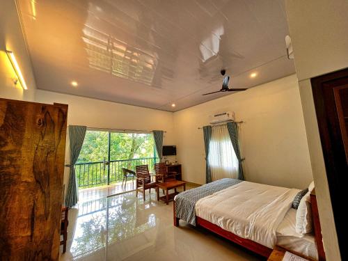 a bedroom with a bed and a desk and a balcony at Meadow Resorts in Vythiri