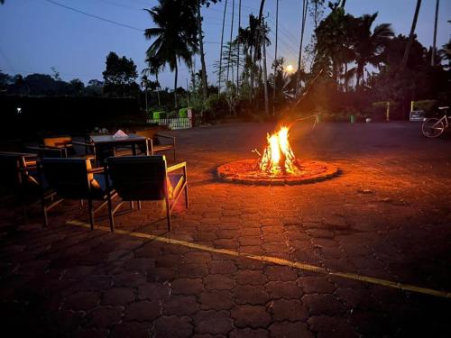 a fire pit in a parking lot with chairs and a table at Meadow Resorts in Vythiri