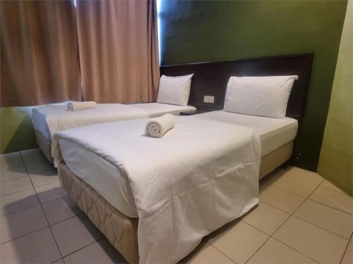 two beds with white sheets in a hotel room at Collection O KLIA Formerly Bary Inn in Sepang