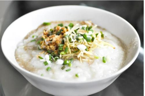 a white bowl of oatmeal with peas and cheese at SCN City Hotel Rayong in Ban Chang