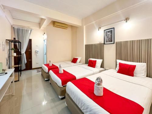 two beds in a hotel room with red pillows at SCN City Hotel Rayong in Ban Chang