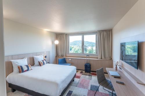 a hotel room with a bed and a desk at Mercure Besancon Parc Micaud - Hotel & Bar in Besançon