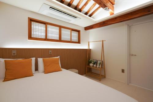 Un dormitorio con una gran cama blanca con almohadas naranjas. en Seoul premium hanok StayDalmaji, en Seúl