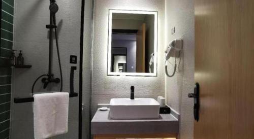 a bathroom with a white sink and a mirror at GreenTree Inn Ganzhou Gan County Bus Station in Ganzhou