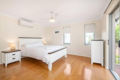 una camera bianca con un letto bianco e un pavimento in legno di Maggies Beach House - Relaxed Stay Near the Beach a Broadwater