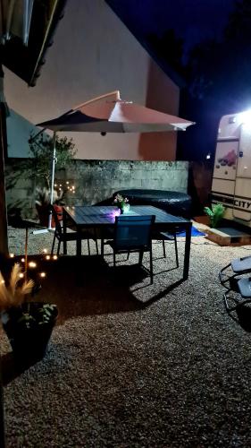 a patio with a table and an umbrella at Caravane Zen & Jacuzzi proche des grottes de Bèze in Bèze