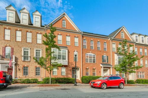 un coche rojo estacionado frente a un gran edificio de ladrillo en Work, Play and Explore DC Area Herndon Haven!, en Herndon