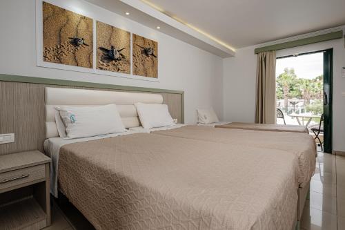 a hotel room with two beds and a balcony at Caretta Beach Resort & WaterPark in Kalamaki