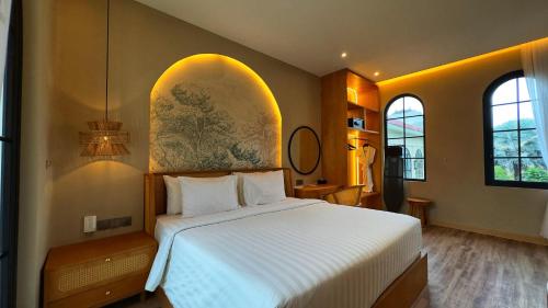 a bedroom with a white bed and two windows at Hygge Hotel and Villas Seminyak in Seminyak