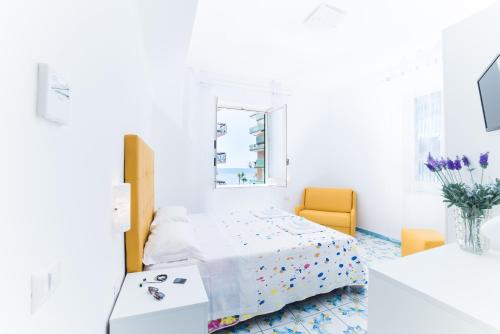 a white room with a bed and a yellow chair at La Casa di Aurora in Maiori