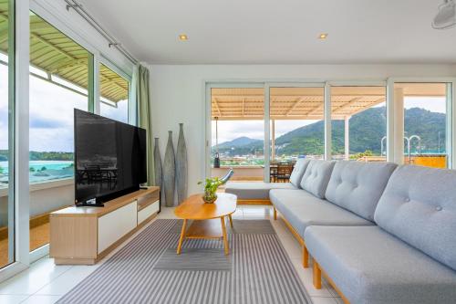 a living room with a couch and a flat screen tv at Kata Hill Sea View Hotel in Kata Beach