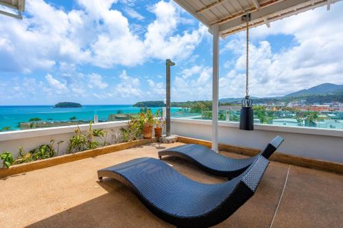 a blue chair on a balcony with a view of the ocean at Kata Hill Sea View Hotel in Kata Beach