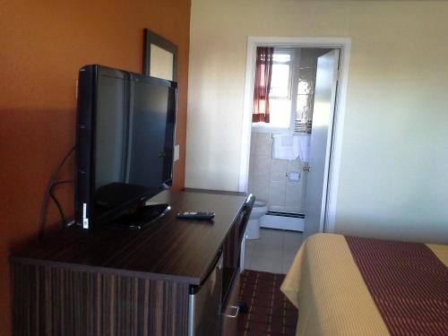 a hotel room with a flat screen tv on a dresser at Budget Inn Tonawanda in Tonawanda