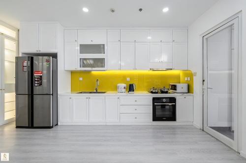 a kitchen with white cabinets and a black refrigerator at The Peak Suite at Landmark Plus in Ho Chi Minh City