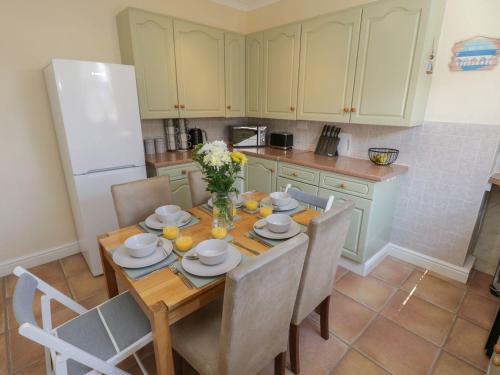 a kitchen with a wooden table with chairs and a refrigerator at Coastal Corner in Whitby