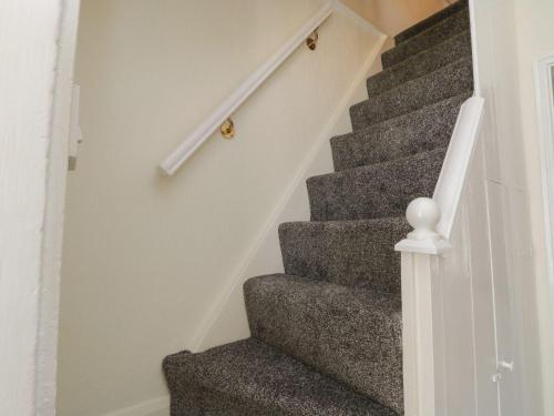 a staircase with grey carpeting and a white stair railing at Coastal Corner in Whitby