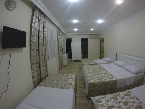 a hotel room with three beds and a flat screen tv at Pınar Vintage House in Pamukkale