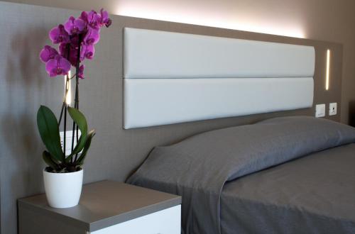 a bedroom with a bed with a vase with purple flowers at GFH - Hotel Sole Resort & Spa in Marotta