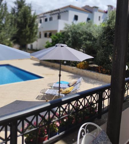 a table with an umbrella next to a pool at Villa Penelope Luxury Retreat with Pool & Timeless Charm in Douliana