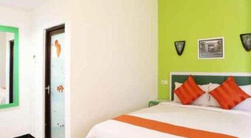 a bedroom with a bed with orange and green walls at Oriza Hotel Surabaya in Surabaya