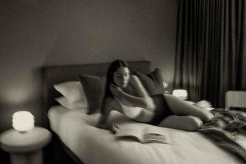 a woman laying on a bed reading a book at Drifter Byron Bay in Byron Bay