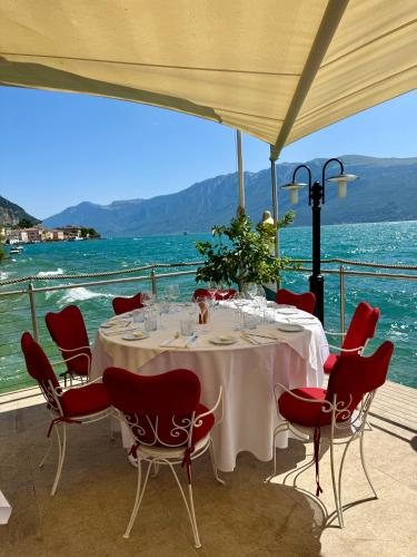 a dining table with red chairs and a view of the water at Hotel Baia D'Oro - Adults Only in Gargnano