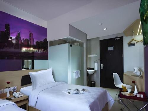 a bedroom with a large white bed and a chair at G Suites Hotel By AMITHYA in Surabaya