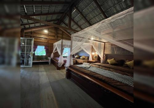 a bedroom with a large bed in a wooden building at Phum Khnhom Bungalow in Battambang