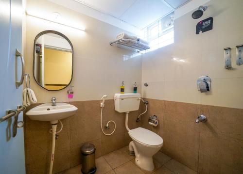 a bathroom with a toilet and a sink and a mirror at Olive Zip Domlur by Embassy Group in Bengaluru
