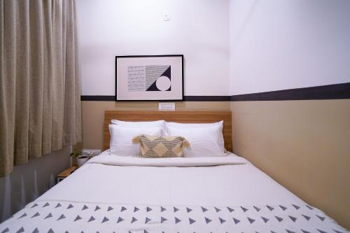 a bedroom with a bed with white sheets and pillows at Olive Zip Domlur by Embassy Group in Bengaluru