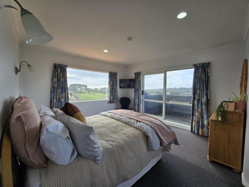 a bedroom with a bed and a large window at Fitzroy Holiday Home ideal for Groups and Families in New Plymouth