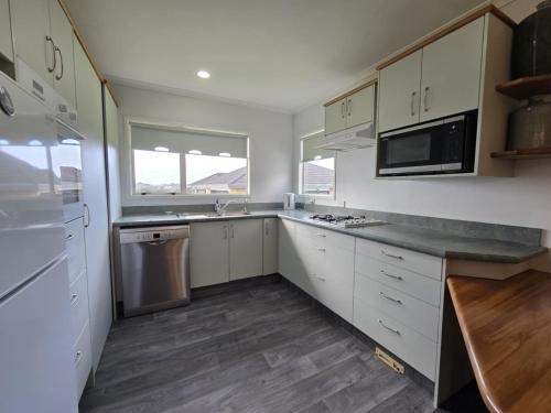 a kitchen with white cabinets and a counter top at Fitzroy Holiday Home ideal for Groups and Families in New Plymouth