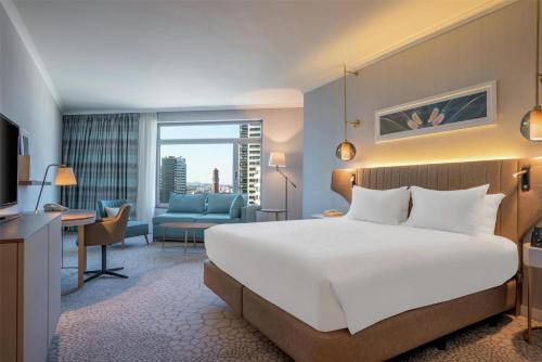 a hotel room with a bed and a living room at Hilton Diagonal Mar Barcelona in Barcelona