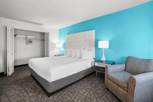 a bedroom with a white bed and a chair at Howard Johnson by Wyndham Columbus Fort Moore in Columbus