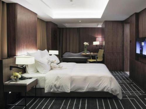 a bedroom with a large white bed and a television at Chongqing The Lotus Hotel in Chongqing