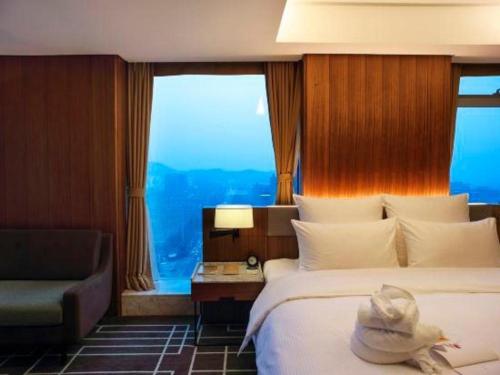 a hotel room with a bed and a chair at Chongqing The Lotus Hotel in Chongqing