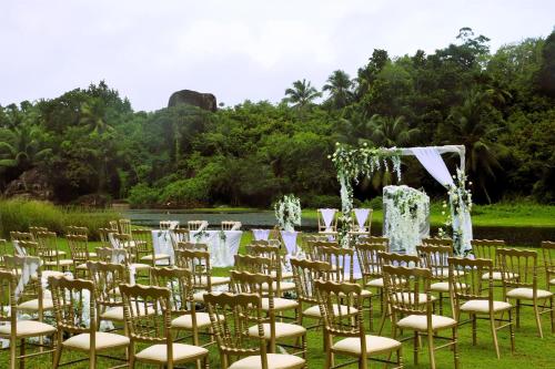 a row of chairs and a altar in front of a lake at Kempinski Seychelles Resort in Baie Lazare Mahé