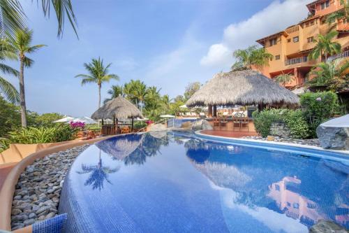 a pool at a resort with chairs and umbrellas at Hilton Grand Vacations Club Zihuatanejo in Zihuatanejo