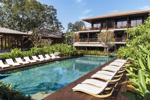 a swimming pool with lounge chairs and a building at Andaz Pattaya Jomtien Beach, By Hyatt in Na Jomtien