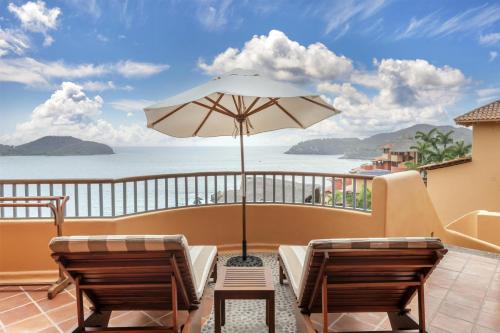 a balcony with two chairs and an umbrella at Hilton Grand Vacations Club Zihuatanejo in Zihuatanejo