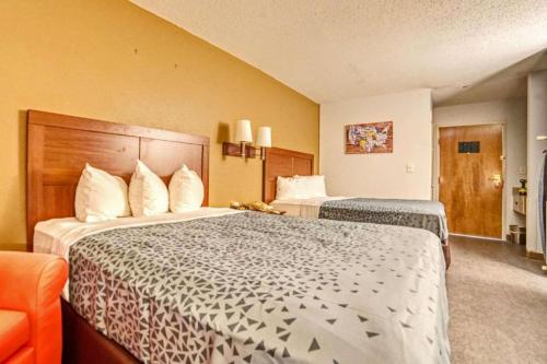 a hotel room with two beds and an orange chair at Econo Lodge Raleigh near Walnut Creek Amphitheatre in Raleigh