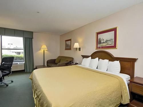a hotel room with a large bed and a chair at Econo Lodge Raleigh near Walnut Creek Amphitheatre in Raleigh